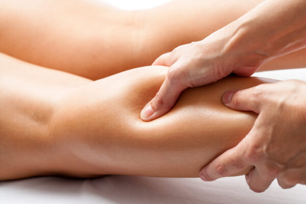 Relief Extreme close up of osteopath applying pressure with thumb on female calf muscle.